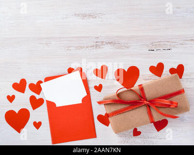 Symbole de la Saint-Valentin - boîte-cadeau en kraft papier marron avec ruban rouge, enveloppe avec une feuille de papier blanche et propre sur fond blanc avec beaucoup de Banque D'Images