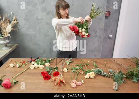 European shop concept. Femme fleuriste crée belle rouge bouquet de fleurs. Beau bouquet frais. L'éducation, master class et Banque D'Images