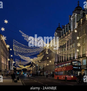 Décorations de Noël Anges et étoiles au-dessus de la rue Regent, Saint James, Londres, avec un bus à impériale rouge et l'extérieur des bâtiments. Saison de Noël. Banque D'Images