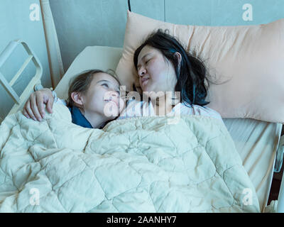 Mère et fille asiatique pose en hosital lit ensemble Banque D'Images