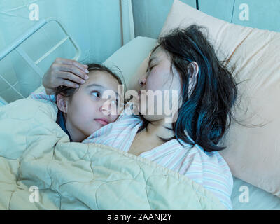 Mère et fille asiatique pose en hosital lit ensemble Banque D'Images