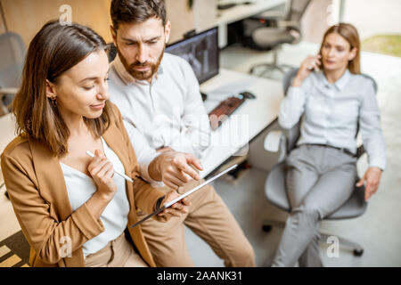 Avoir des collègues de travail créatif à l'aide de tablette numérique et un crayon à l'office moderne studio. Concept de la conception sur une tablette numérique Banque D'Images