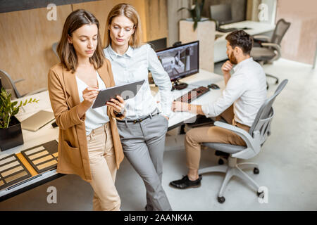 Avoir des collègues de travail créatif à l'aide de tablette numérique et un crayon à l'office moderne studio. Concept de la conception sur une tablette numérique Banque D'Images