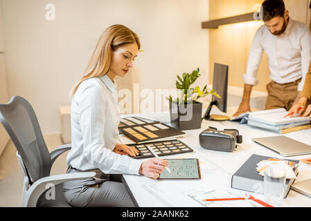 Les jeunes employés habillés à la légère de faire certains travaux de création à la grande table avec les ordinateurs dans le bureau. Concept d'une entreprise d'architecture et de création Banque D'Images
