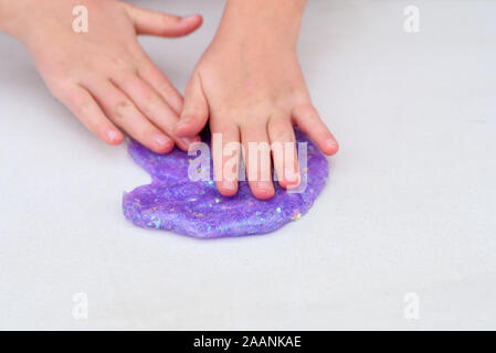 Processus de mucus. Purple glitter magic slime sur un fond blanc. Slime froisse l'enfant. Close up of hands. Banque D'Images