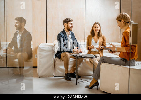 Jeune couple talking with woman comme sales manager, conseiller ou psychothérapeute, assis sur le confortable canapé dans le bureau Banque D'Images