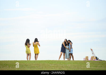 Certaines filles de différents groupes ethniques sont à prendre des photos de l'autre dans un parc public à Singapour. Banque D'Images