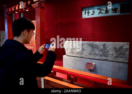 Nanyang, province de Henan en Chine. 22 Nov, 2019. Un visiteur prend des photos d'une exposition à la Nanyang Stone-Carved Art Museum de Nanyang, province de Henan en Chine centrale, du 22 novembre 2019. Fondée en 1935, le musée de sculptures sur pierre de la dynastie Han propose plus de 2 000 expositions de sculpture en pierre découverts à mausolées construite entre la fin du troisième siècle avant J.-C. et le début du troisième siècle de notre ère. Credit : Feng Pingyao/Xinhua/Alamy Live News Banque D'Images