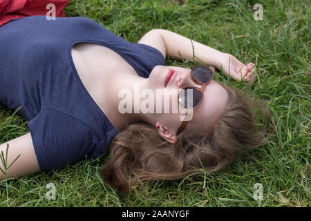 Jeune femme caucasienne mignonne dans des verres sur le champ d'herbe Banque D'Images