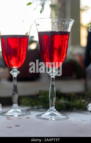 Vin rouge dans des verres transparents. Sur un fond clair. Arrière-plan flou derrière. Les branches d'arbre de Noël. Copier l'espace. Banque D'Images