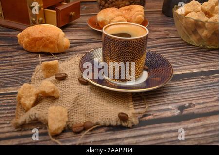 Une tasse de café, des morceaux de sucre dans un sucrier et croissants sur un fond de bois Banque D'Images
