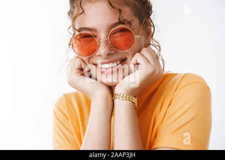 Close-up heureux plaisir ludique insouciante jeune fille rousse portant des lunettes de soleil orange t-shirt chilling station au cours de voyage vacances blanc permanent Banque D'Images