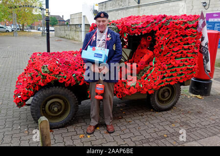 Vendeur pavot Arthur Smith de Heytesbury se tient juste en face de son WW2 jeep militaire américain orné de coquelicots en tricot Banque D'Images