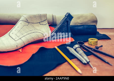 Outils d'artisanat du cuir sur fond de bois. Lieu de travail pour cordonnier. Morceau de cuir. Avec des outils de travail du cordonnier, cuir et chaussures en dernier. Petit shoem Banque D'Images