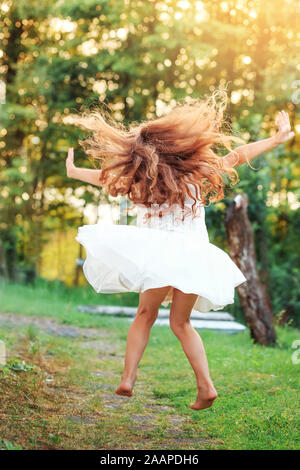 Belle petite fille est la danse à l'extérieur de l'été au coucher du soleil. L'accent doux Banque D'Images