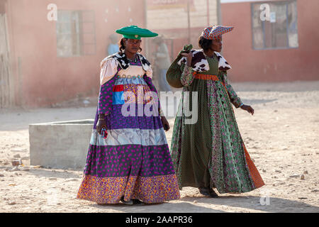 Les femmes Herero en vêtements traditionnels et chapeau cornu à pied dans une rue d'Opuwo ville en Namibie, Afrique Banque D'Images