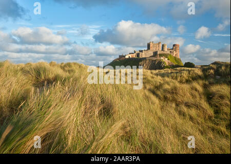 Château de Bamburgh haut perchées sur des rochers escarpés surplombant les dunes côtières, de la plage et de la mer du Nord. Northumberland, Angleterre Banque D'Images