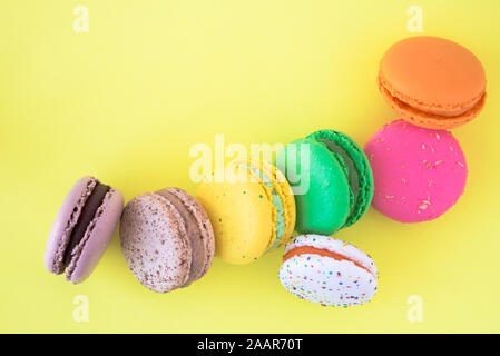 Biscuits macaron français colorés sucré sur fond jaune pastel, vue du dessus Banque D'Images