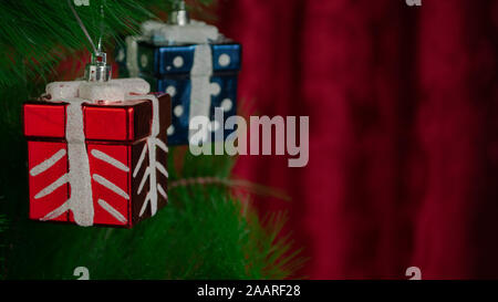 Décorations de cadeaux sur l'arbre de Noël devant un fond rouge avec espace de copie, illustration-photo Banque D'Images