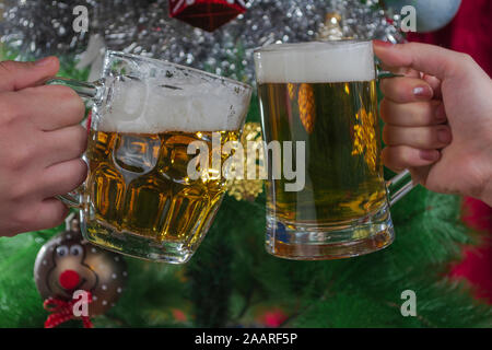 Bonne Année. Deux personnes en train de griller deux pintes de bière légère devant l'arbre de Noël, photo-illustration Banque D'Images