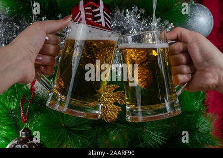 Bonne Année. Deux personnes en train de griller deux pintes de bière légère devant l'arbre de Noël, photo-illustration Banque D'Images