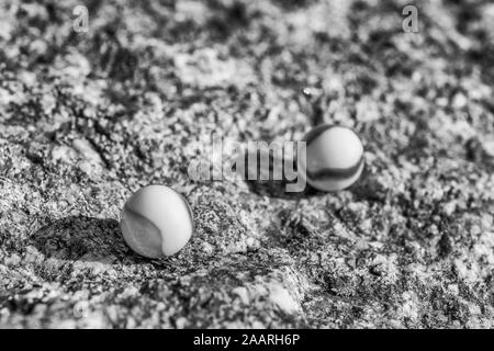 Billes de verre noir et blanc sur une surface en pierre rugueuse. Pour quelque chose perdu, santé mentale, perdre vos billes, sphères abstraites, rêves, Biden et billes. Banque D'Images