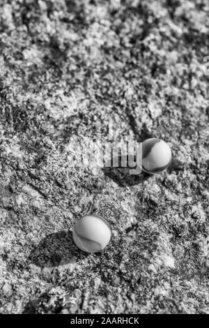 Billes de verre noir et blanc sur une surface en pierre rugueuse. Pour quelque chose perdu, santé mentale, perdre vos billes, sphères abstraites, rêves, Biden et billes. Banque D'Images