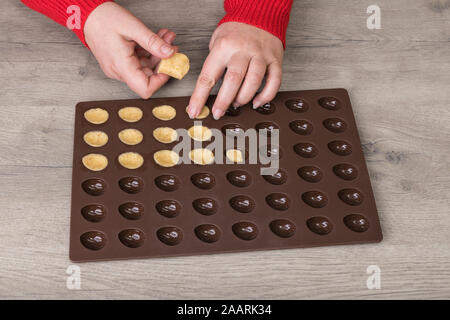 Les matières de remplissage biscuit pâte brisée pâte en moule à pâtisserie en silicone sur un fond de bois. Femmes détail et friandises de Noël traditionnel en forme de l'écrou. Banque D'Images