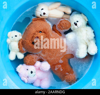 Faire tremper les ours de jouet dans l'eau lessive dissolution avant le lavage. Blanchisserie concept, vue d'en haut Banque D'Images