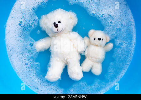 Faire tremper les ours de jouet dans l'eau lessive dissolution avant le lavage. Blanchisserie concept, vue d'en haut Banque D'Images