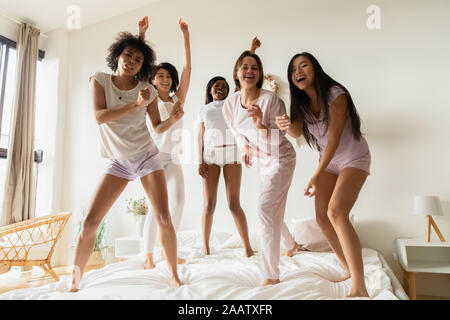 Funny multiraciale positive mesdames dancing on bed looking at camera Banque D'Images