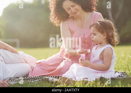 Une jolie petite fille est passer du temps avec son grand-père bien-aimé et grandmather dans le parc. Ils avaient un pique-nique sur l'herbe Banque D'Images