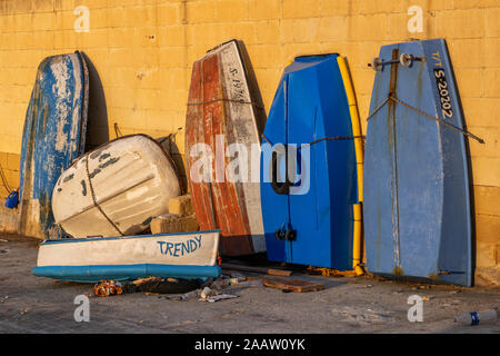 Petit vieux bateaux, dingies laissés sécher, certains verticalement, sécurisé par chaîne à un mur, l'île Manoel quay à Malte Banque D'Images