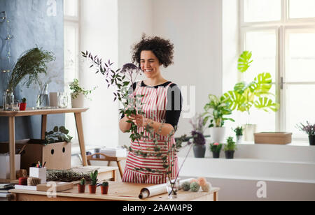 Happy young woman arranging flowers dans une petite boutique Banque D'Images