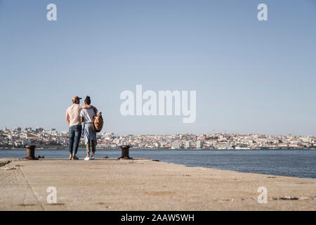 Jeune couple debout sur une jetée à la mer, Lisbonne, Portugal Banque D'Images