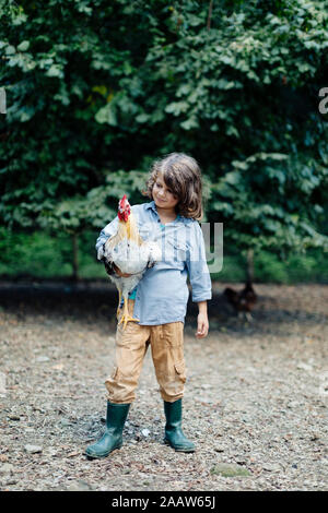 Boy holding chicken sur une ferme biologique Banque D'Images