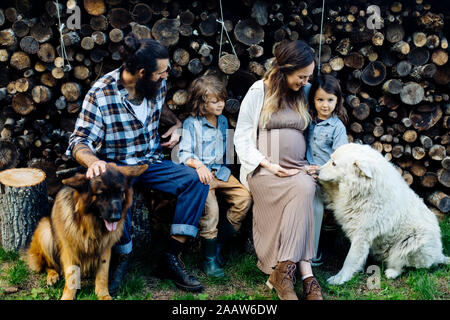 Famille avec deux chiens relaxant à la pile de bois Banque D'Images