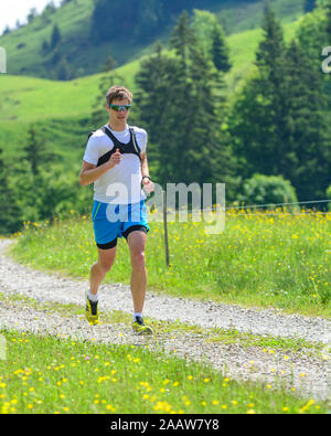 L'homme faisant une séance de course en vert nature alpine Banque D'Images