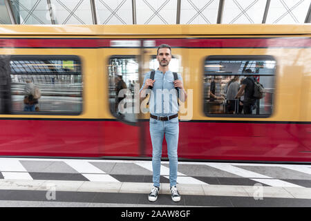Portrait de l'homme à la plate-forme de la gare avec train en arrière-plan, Berlin, Allemagne