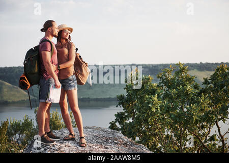 Deux mâles et de tourisme femme avec des sacs à dos sont au sommet de la montagne et profiter de l'aube. Style de voyage vacances d'aventure concept Banque D'Images