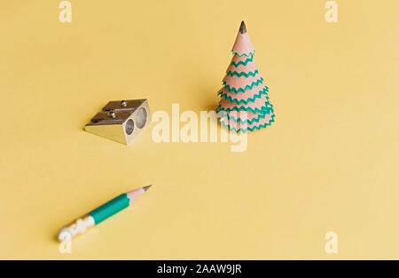 Arbre de Noël créatif. Copeaux de crayon, crayon et taille-crayons sur un fond jaune. Concept de Noël dans le bureau. Focus sélectif. Close up. Banque D'Images