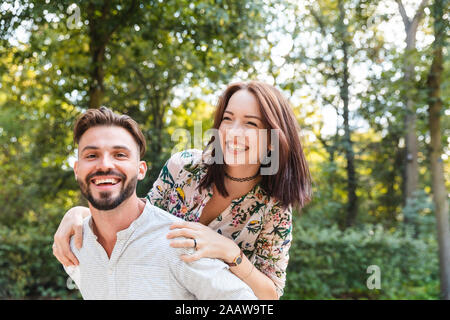 Portrait of happy young man giving his girlfriend a piggyback ride Banque D'Images