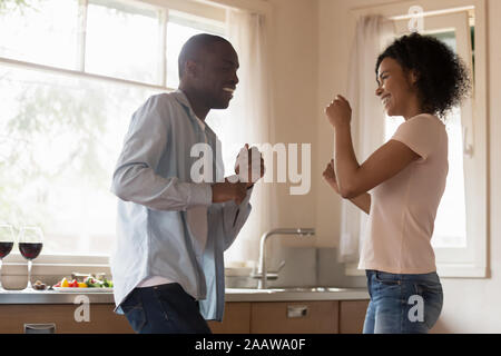 Heureux couple biracial amusez danser dans la cuisine Banque D'Images