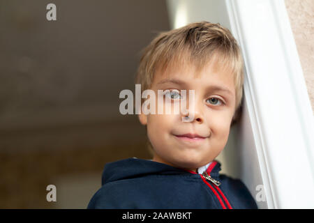 Portrait of little boy leaning against door Banque D'Images