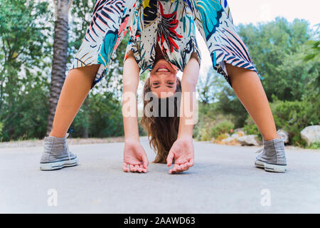 Vue arrière de rire jeune femme se regardant à travers ses jambes Banque D'Images