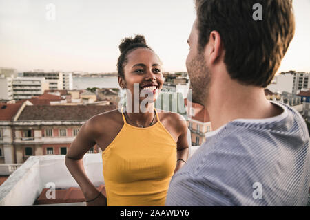 Happy young couple talking sur toit dans la soirée Banque D'Images