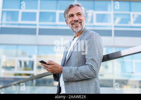 Smiling mature woman with cell phone outdoors Banque D'Images