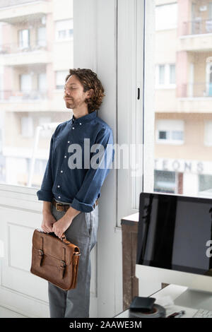 Man holding sac dans un studio appuyé contre la fenêtre Banque D'Images