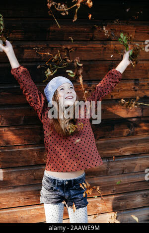 Smiling girl debout devant un mur en bois avec bras tendus à l'extérieur Banque D'Images