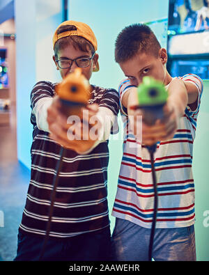 Portrait d'amis adolescents tir avec des pistolets en une salle de jeux électroniques Banque D'Images